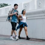 A couple enjoys a city walk together, capturing moments with a camera.